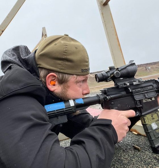 Darin Ellington aiming a rifle with an optic