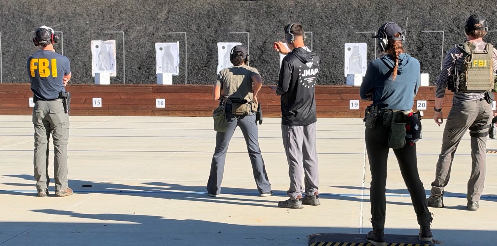 Law enforcement trainees on a range line, with a JMAP instructor timing shooters at their targets