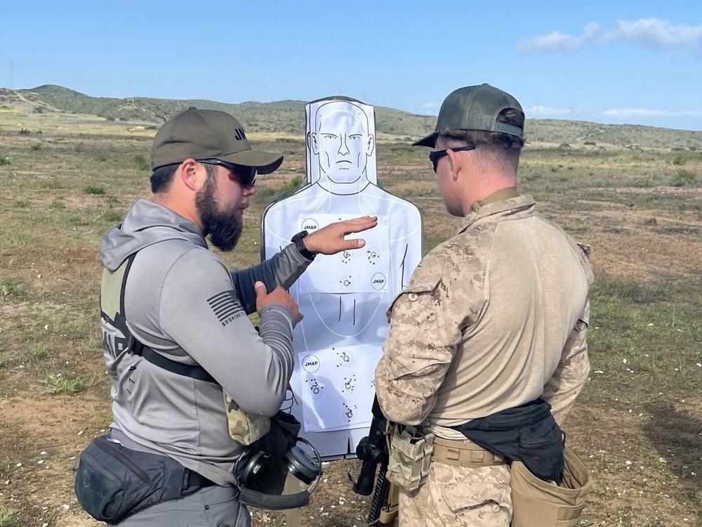 A JMAP instructor reviewing a scored target with a Marine on the range
