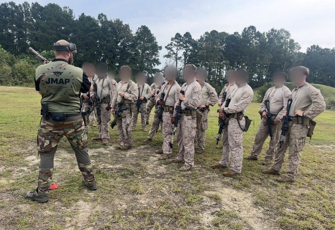 A Scoring Tech instructor briefing a class of service members on the range; faces blurred