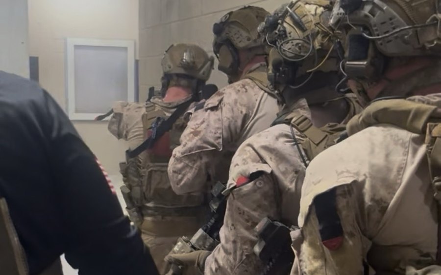 A team stacked up in a hallway, moving to clear a room